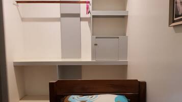 Un dormitorio con cama, cabecera de madera, estantería empotrada y una puerta.
