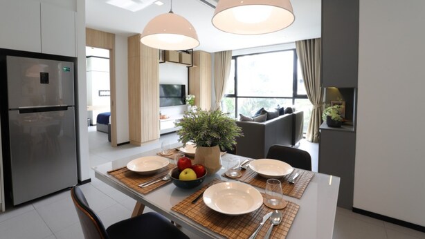 A modern kitchen with a built-in refrigerator, a dining table set with plates, cutlery, and a bowl of fruit. - Alix Bangkok Hotel (Bangkok)