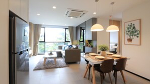 A modern living room with a sofa, dining table, and chairs. There is a refrigerator, a coffee table, and a potted plant. - Alix Bangkok Hotel (Bangkok)