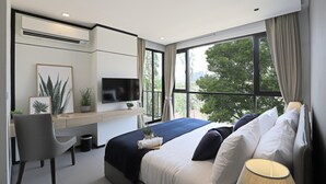 A modern bedroom with a bed, a desk, a TV, and a large window. - Alix Bangkok Hotel (Bangkok)