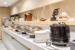 Montaje de bufé con diferentes recipientes de comida, una máquina de café y una rueda decorativa.