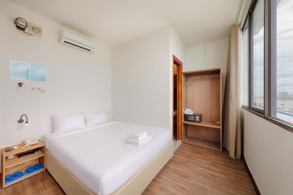 Une chambre d’hôtel équipée d’un lit, d’une armoire, d’une fenêtre et d’un climatiseur fixé au mur.