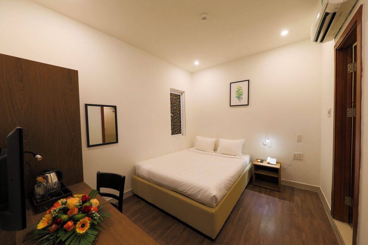 A bedroom with a bed, bedside table, and a desk with a chair.