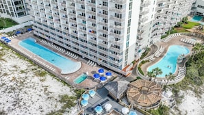 Un hotel de gran altura con varios balcones, una piscina central y una zona de piscina separada.