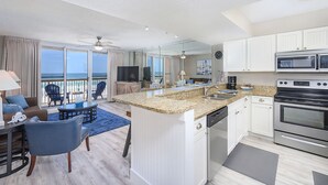 Una cocina moderna con una isla grande, armarios blancos y electrodomésticos de acero inoxidable.