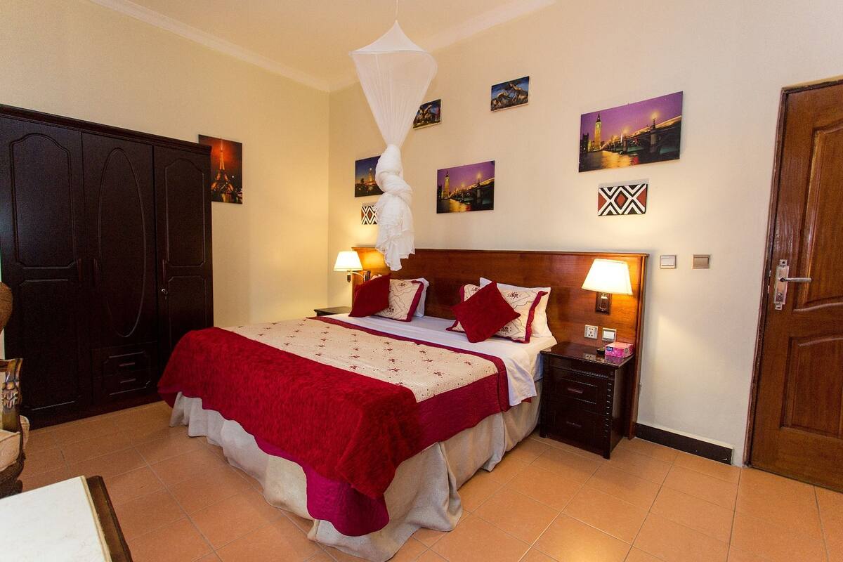 Un dormitorio con cama, mesitas de noche, armario y puerta.