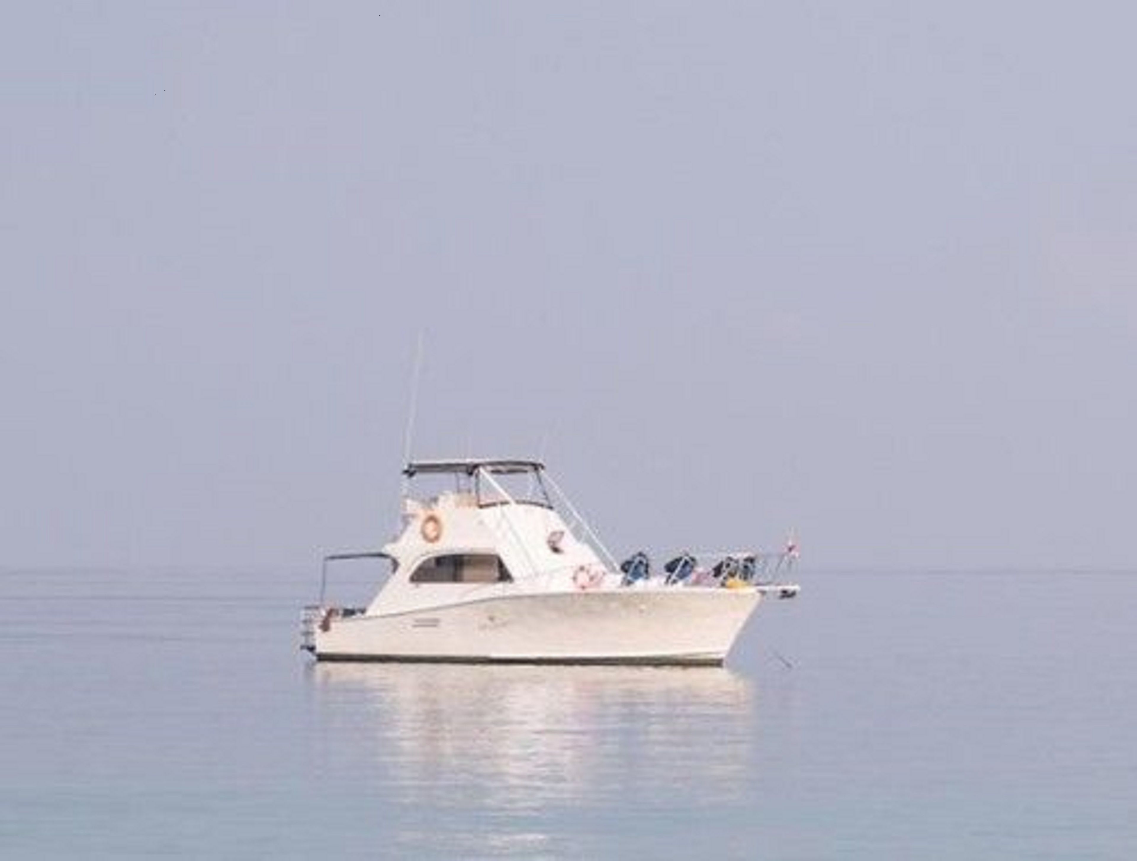 Una pequeña embarcación blanca sobre aguas tranquilas.