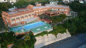 A large, multi-story hotel with a rooftop pool and multiple balconies. - Hotel Garden Hills (Kumejima)