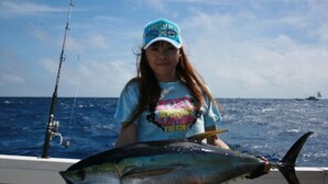 A person holding a large fish on a boat with the ocean in the background. - Hotel Garden Hills (Kumejima)