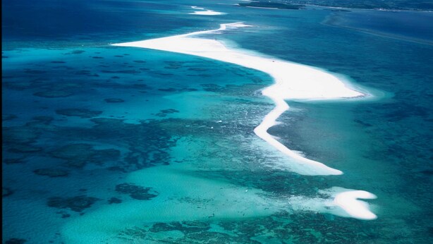 An aerial view of a coastal area with clear blue waters and white sandy beaches. - Hotel Garden Hills (Kumejima)