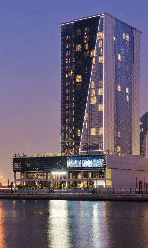 A modern high-rise building with a prominent triangular glass facade. - Canal Central Hotel (Dubai)