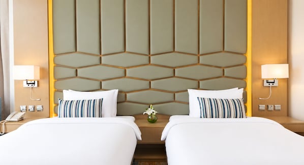 A hotel room with two beds, a geometric-patterned headboard, bedside lamps, a telephone, and a vase with flowers. - Canal Central Hotel Business Bay (Dubai)