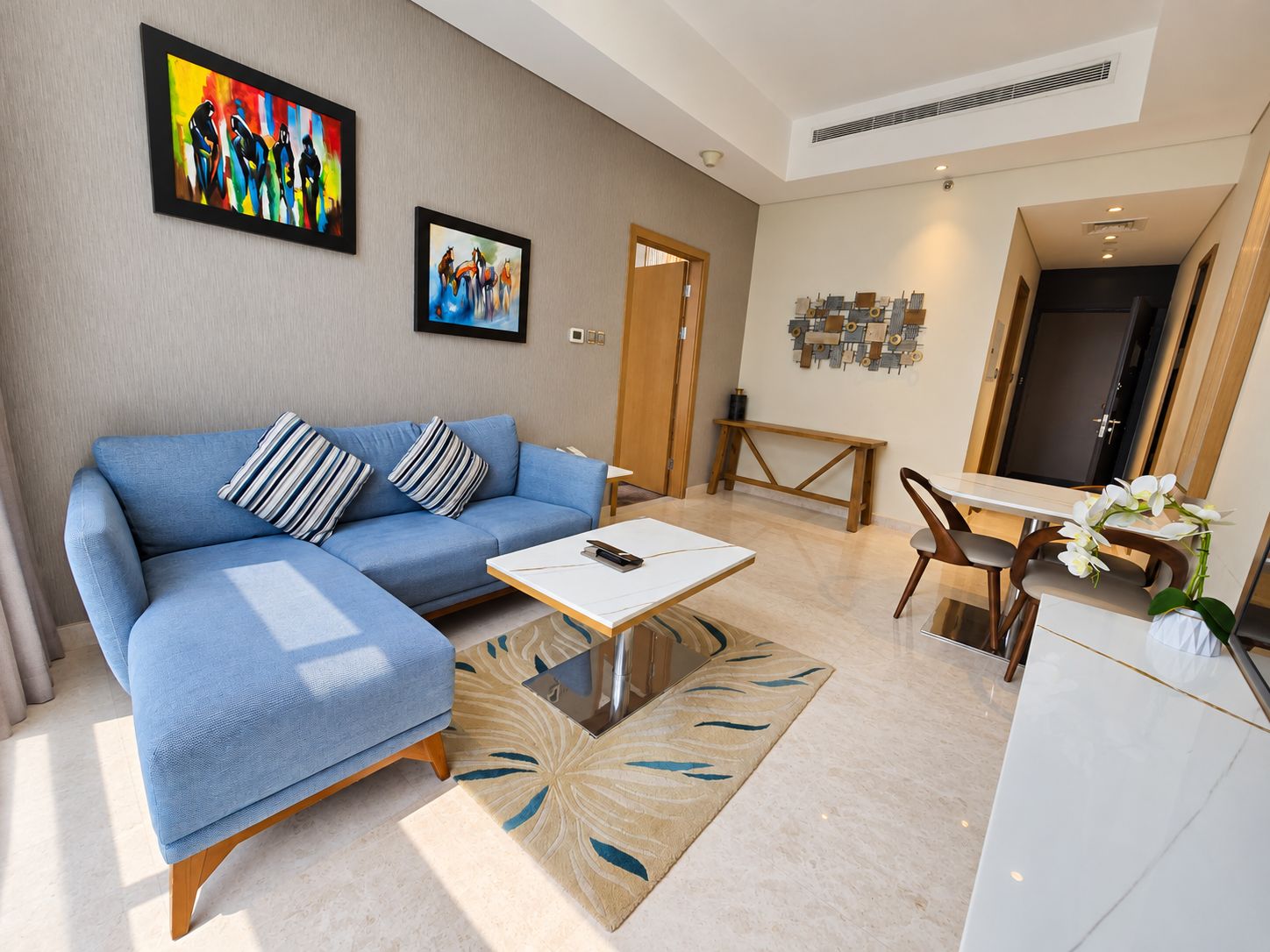 A modern living room with a blue sofa, a coffee table, and artwork on the walls.
