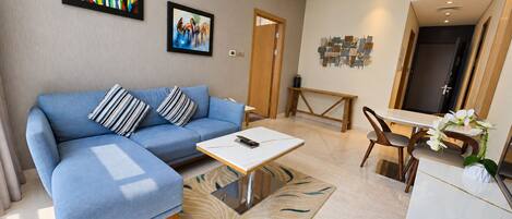 A modern living room with a blue sofa, a coffee table, and artwork on the walls.