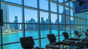 Une salle de sport équipée de vélos d’appartement et offrant une vue sur les toits d’une ville et sur l’eau.