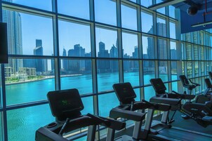 Un gimnasio con bicicletas estáticas y vista al horizonte urbano y al agua.