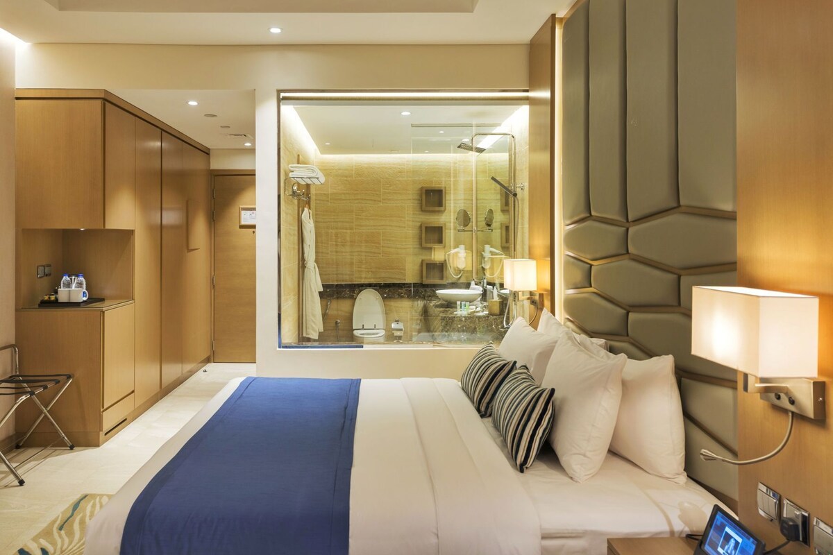 Une chambre d’hôtel avec un lit, une table de chevet, une lampe et une vue sur la salle de bain.