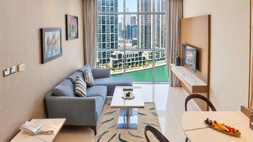 Una sala moderna con sofá, mesa de comedor y vista a un paisaje urbano a través de amplios ventanales.