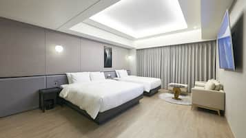 A modern hotel room with a large bed, a sofa, a TV, and a small table.