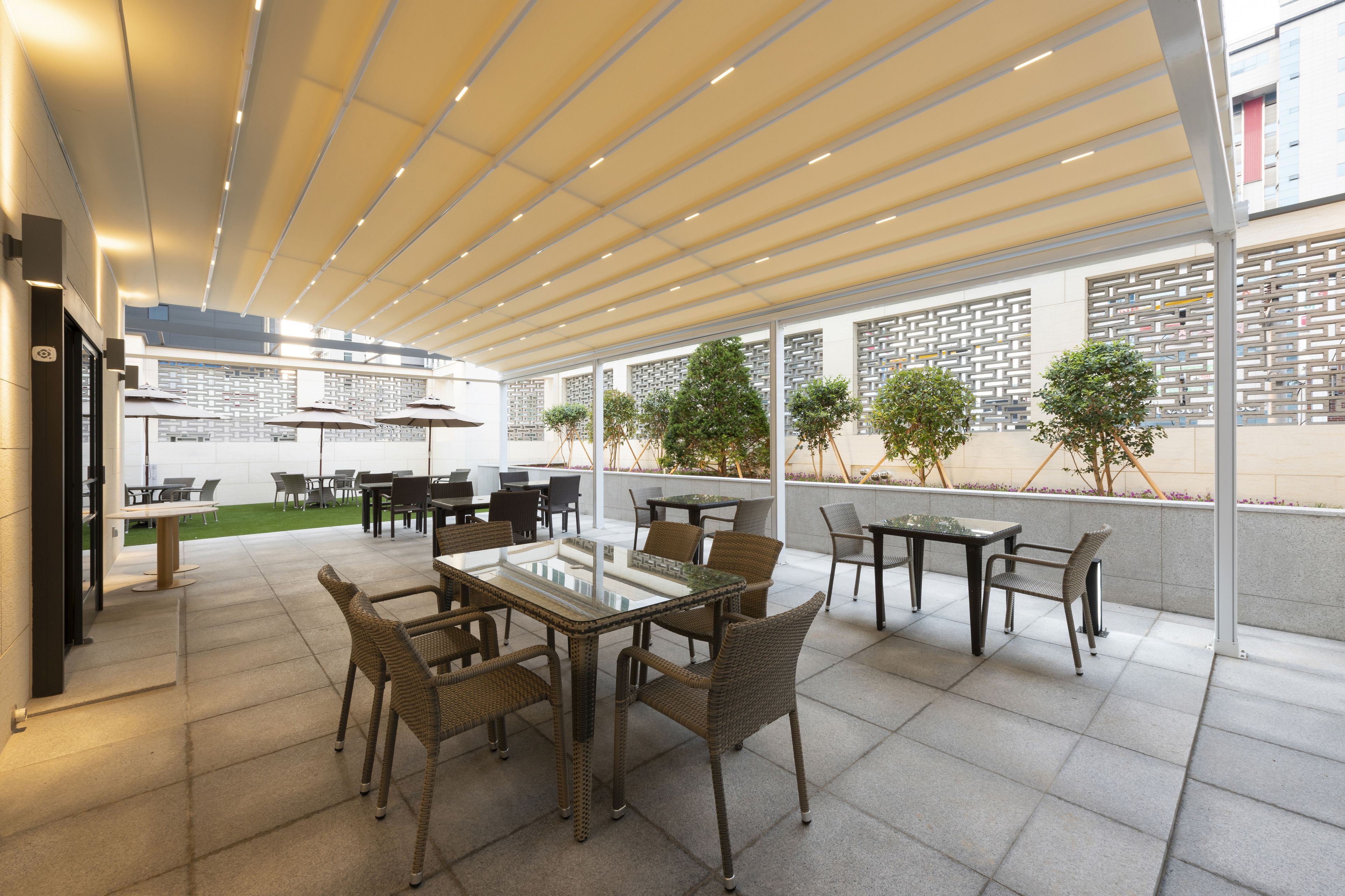 An outdoor patio area with tables and chairs, a covered seating area, and a view of the street.
