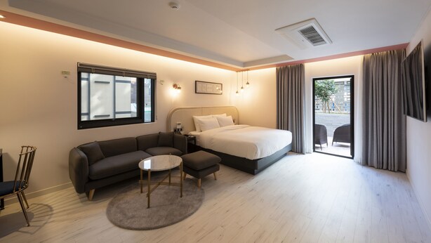 A modern hotel room with a bed, sofa, and a small round table. - Yeonsan Hound Hotel (Busan)