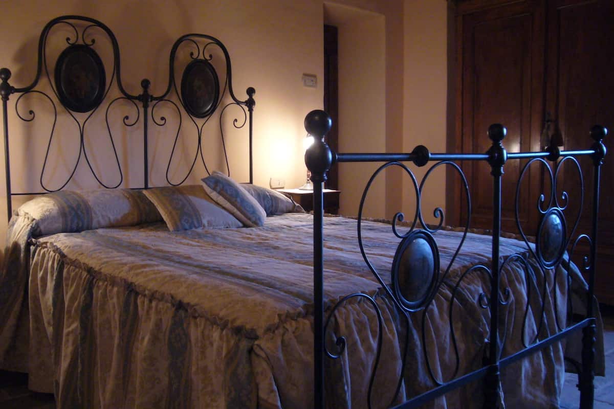 Une chambre à coucher avec un lit en métal, une table de chevet avec une lampe et une commode.