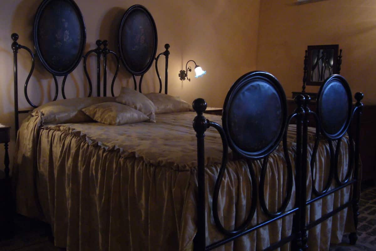 Une chambre à coucher avec un lit, des tables de chevet et des lampes fixées au mur.