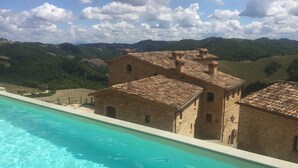 Vistes a la piscina, amb un edifici de pedra i un paisatge de muntanyes al fons.