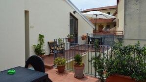 A balcony with potted plants, a table, and a chair. - Borgo800 (San Nicola Arcella)
