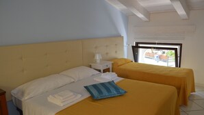 A hotel room with a large bed, two smaller beds, a nightstand with a lamp, and a window with a view of the outside. - Borgo800 (San Nicola Arcella)