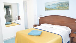 A hotel room with a bed, a nightstand, a mirror, and a painting on the wall. - Borgo800 (San Nicola Arcella)