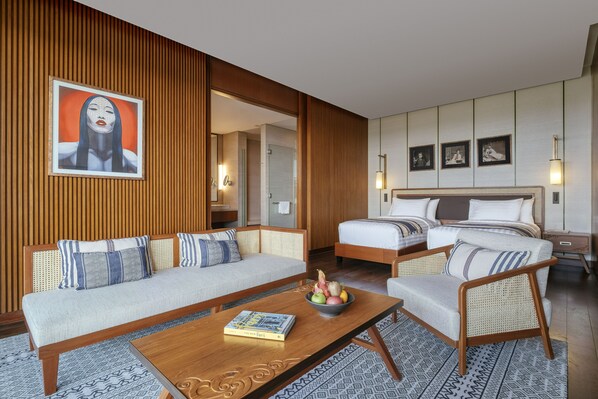 A hotel room with a sofa, two single beds, a wooden coffee table, and a wall with framed artwork. - Awei Metta Yangon (Yangon)