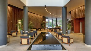 Un hall d’entrée moderne doté d’une fontaine centrale, d’espaces aménagés pour s’asseoir et de grandes colonnes.