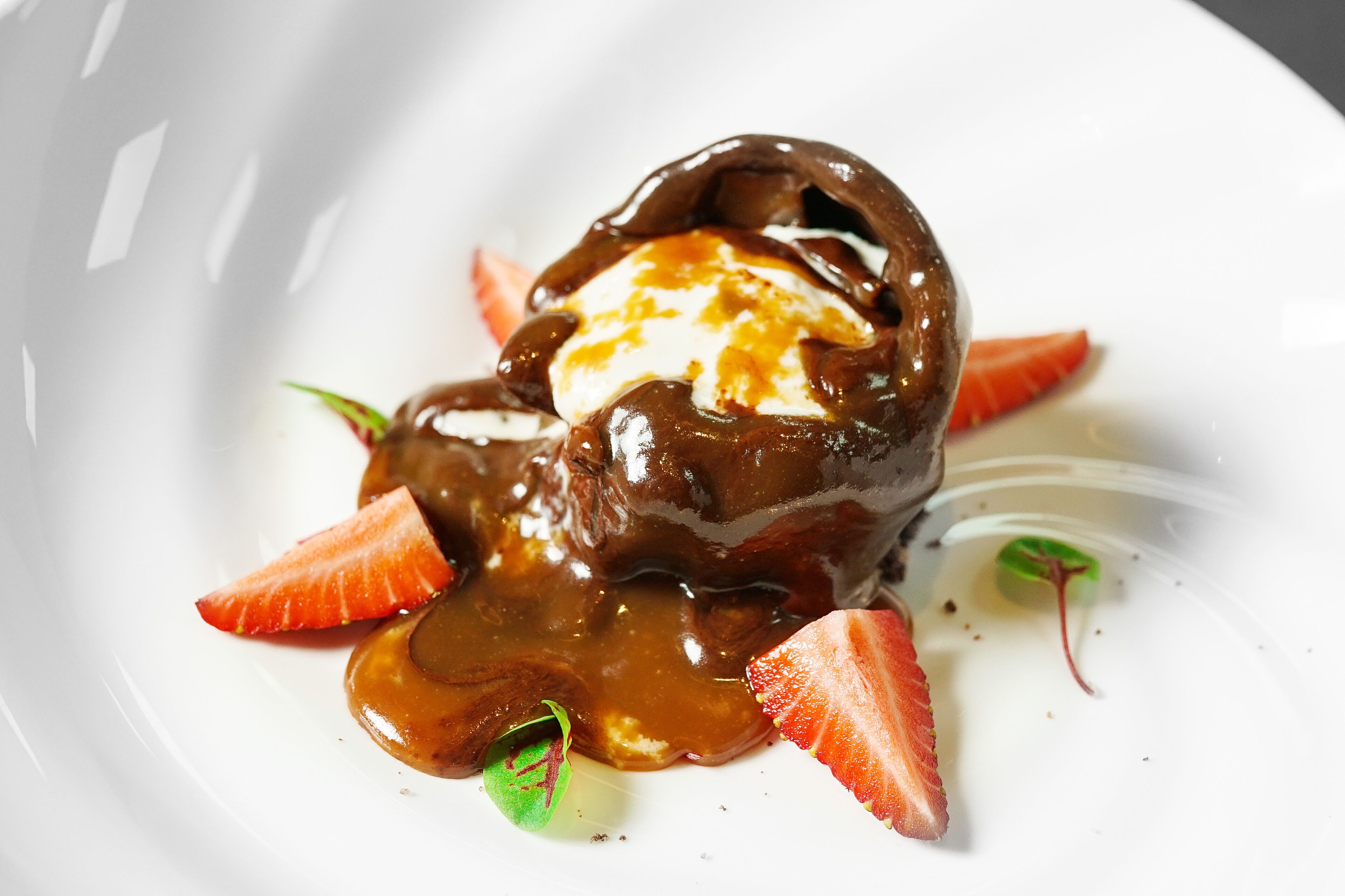A dessert with chocolate sauce and strawberries on a white plate.