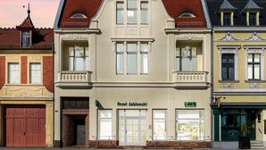 A building with a prominent entrance, a sign reading "René Jałonkowski," and a visible storefront with a green awning. - Apartment Senftenberg - 1907 (Senftenberg)