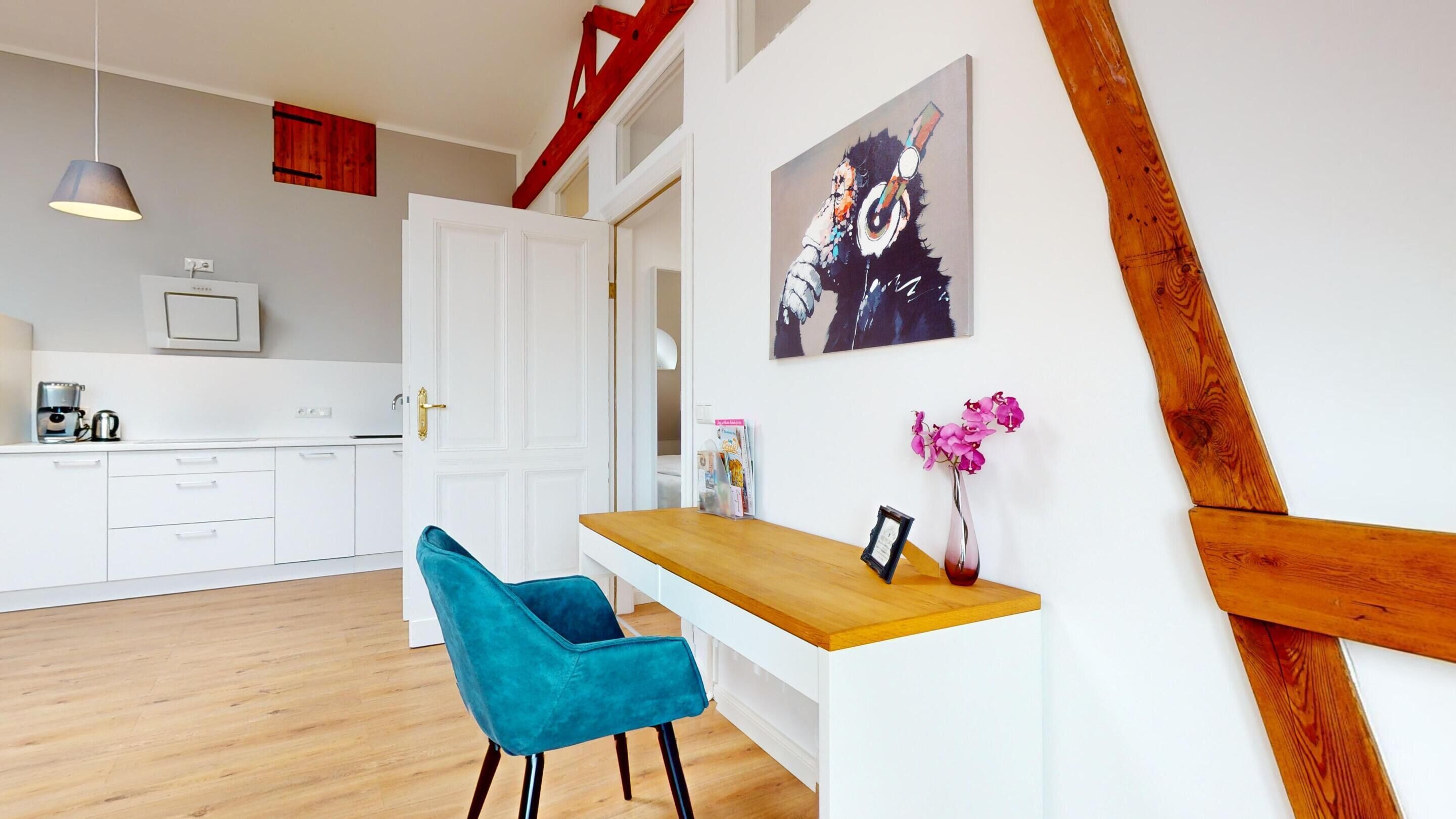 A modern kitchen with white cabinets, a wooden countertop, and a teal chair.