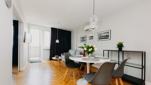 Een moderne eethoek met een ronde tafel, grijze stoelen en een plank met zwarte lijst.