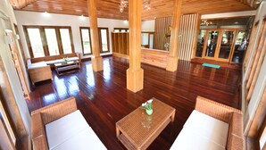 A spacious room with wooden flooring, large windows, and a high ceiling.