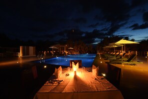 A poolside dining area with a table set for two, overlooking a swimming pool. - Keinnara Loikaw (Loikaw)