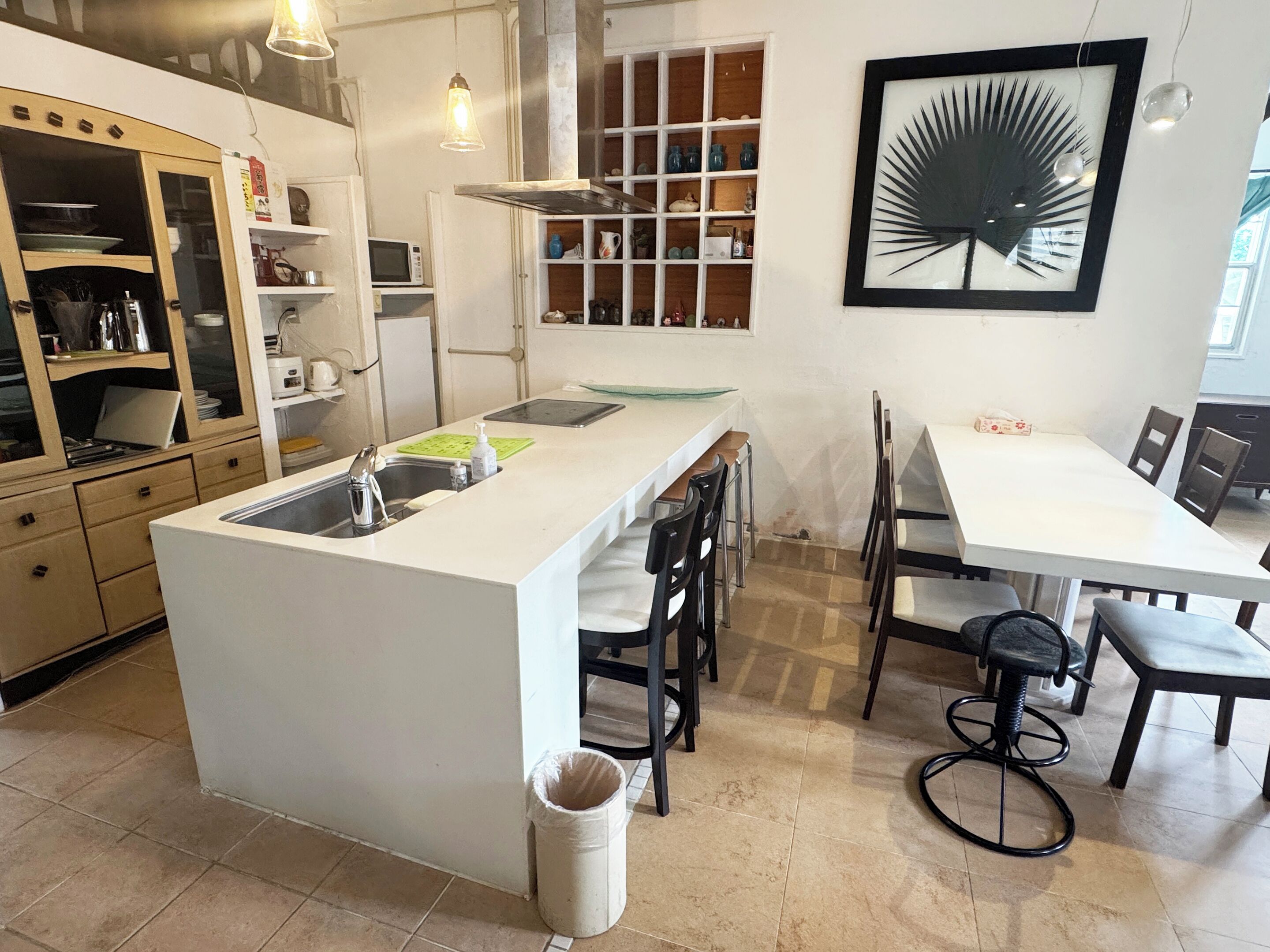 A modern kitchen with a central island, white cabinetry, and a dining area with a white table and chairs.