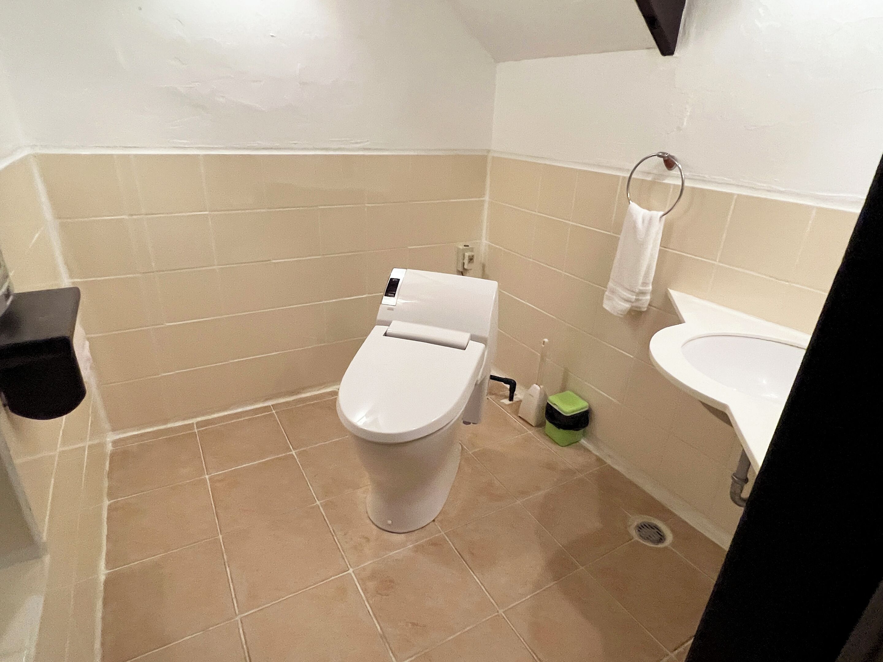 Un baño pequeño con inodoro, lavamanos y un bote de basura.