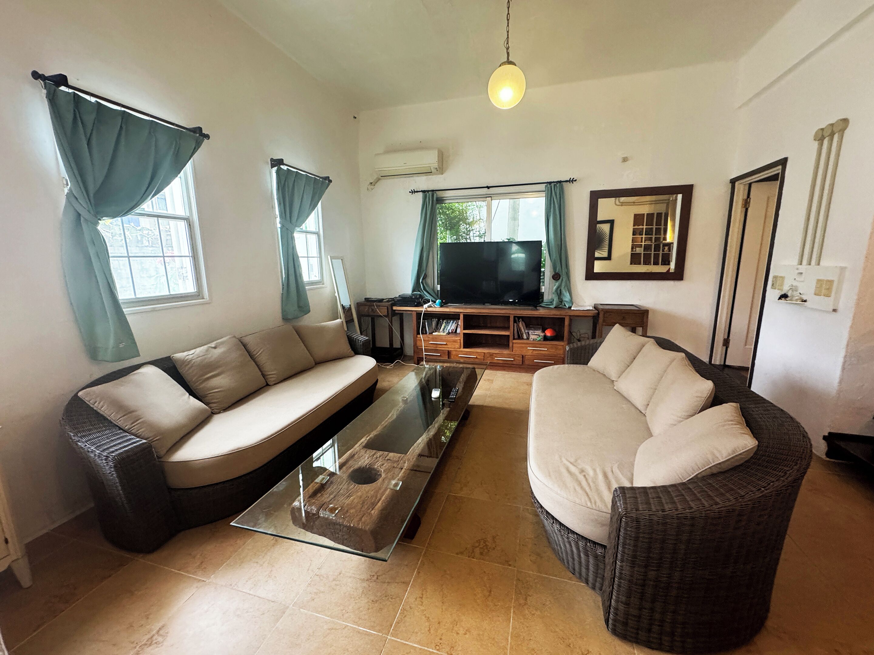 A living room with two sofas, a coffee table, a television, and a window with curtains.