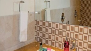 Un baño con encimera de mármol, lavabo, espejo y salpicadero de azulejos.