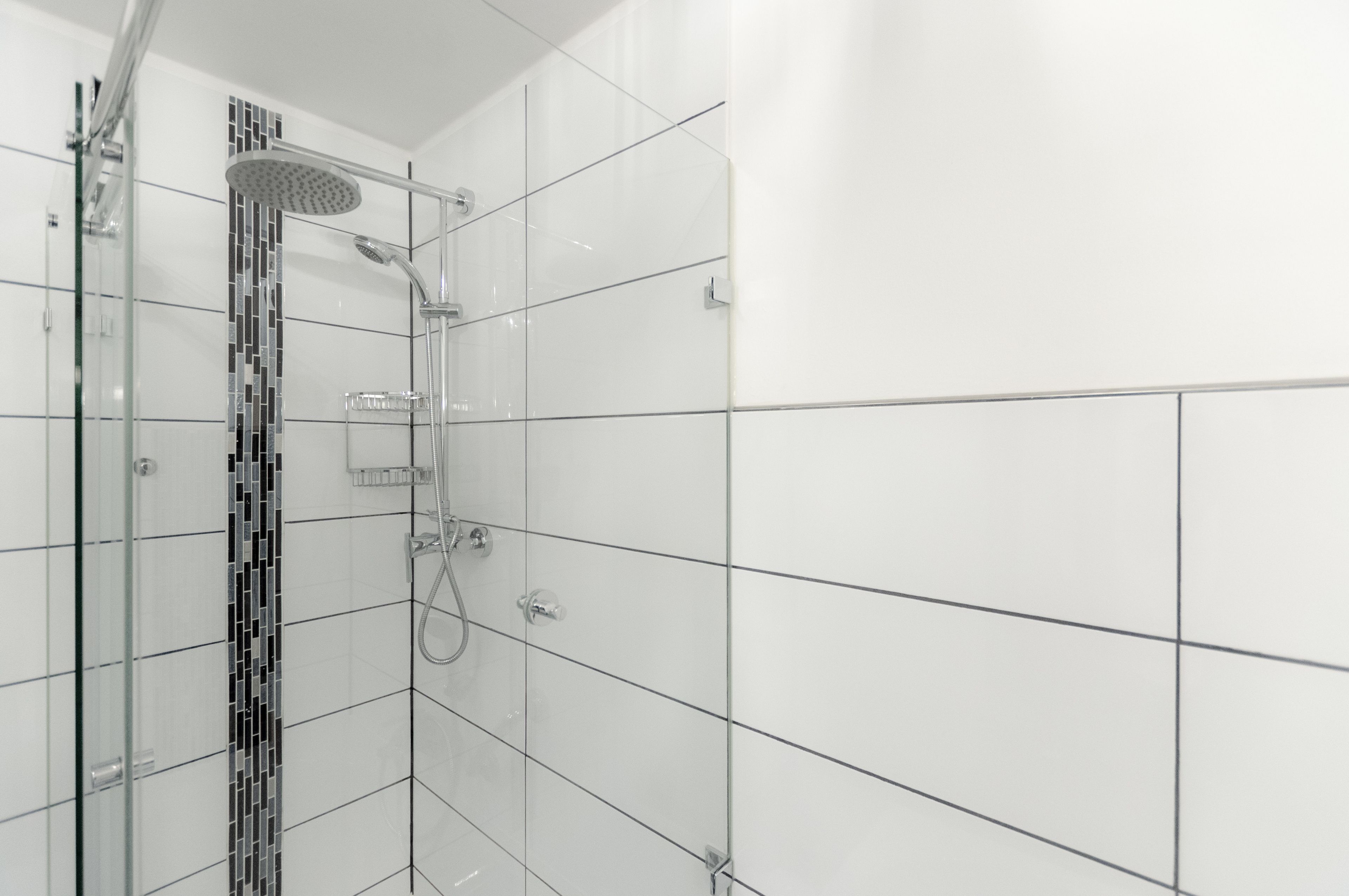 A modern shower area with a glass enclosure, a showerhead, and a control panel.