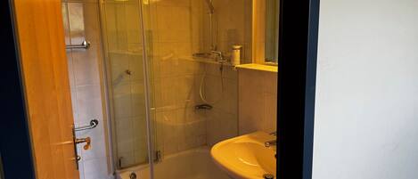 A bathroom with a glass-enclosed shower, a sink, and a mirror.