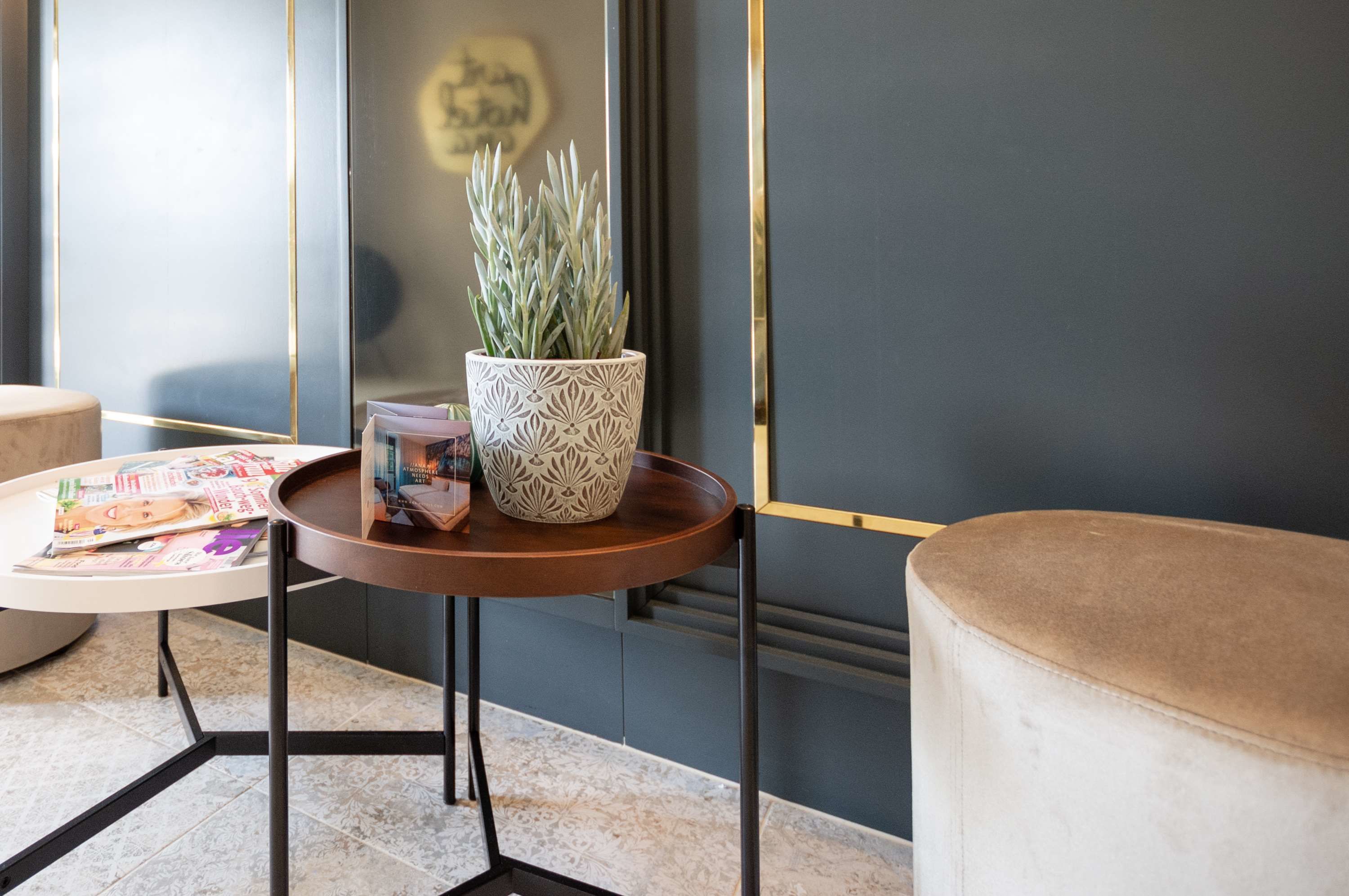 A modern interior with a round table holding magazines and a patterned pot with a plant.