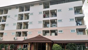 A multi-story hotel with balconies, a covered entrance, and a garden area. - Areechon Apartment (Ban Chang)