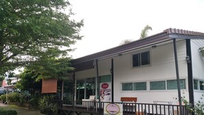 A two-story building with a covered porch, large windows, and a sign advertising a beauty salon. - Areechon Apartment (Ban Chang)