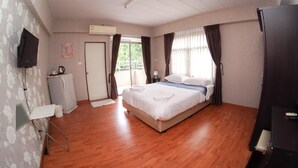 A hotel room with a wooden floor, a bed with white bedding, a flat-screen TV mounted on the wall, a window with curtains, and a door. - Areechon Apartment (Ban Chang)