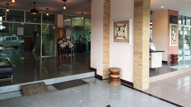 A modern hotel lobby with glass doors, a reception desk, and a decorative wall with a framed picture. - Areechon Apartment (Ban Chang)